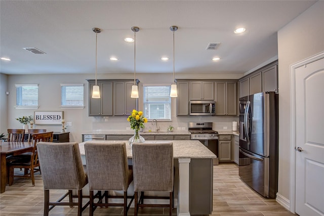 kitchen featuring stainless steel appliances, a center island, wood finish floors, and gray cabinets