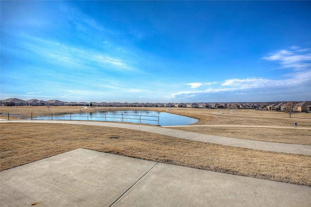 view of swimming pool featuring a water view and a lawn