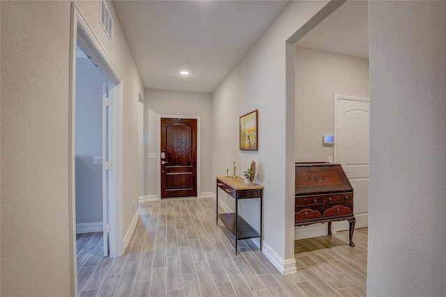 hallway featuring visible vents, baseboards, and wood finish floors