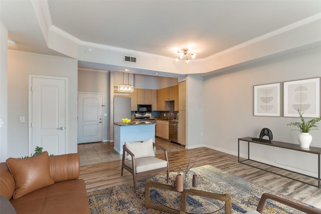 living room featuring light wood-type flooring, crown molding, and a tray ceiling