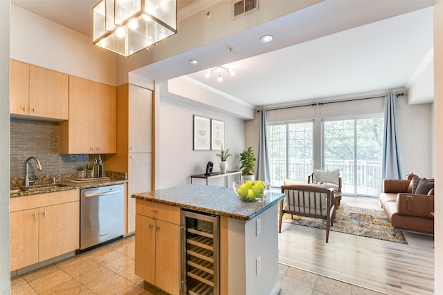 kitchen featuring wine cooler, light brown cabinetry, a kitchen island, sink, and stainless steel dishwasher