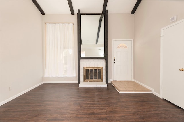 unfurnished living room featuring a fireplace, beam ceiling, and dark wood-type flooring