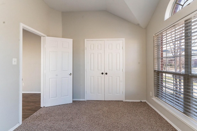 unfurnished bedroom with vaulted ceiling, a closet, and dark carpet