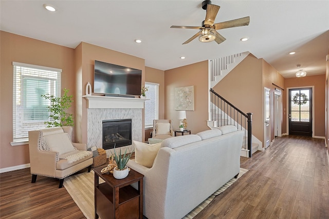 living room featuring a fireplace, ceiling fan, and wood-type flooring