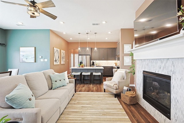 living room featuring a tile fireplace, ceiling fan, and hardwood / wood-style floors