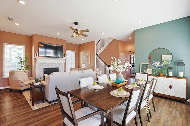 dining space featuring a fireplace, ceiling fan, and hardwood / wood-style flooring