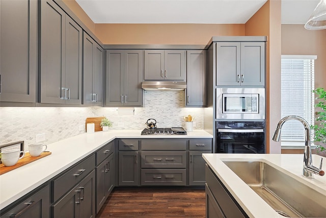 kitchen with sink, stainless steel appliances, tasteful backsplash, gray cabinets, and dark hardwood / wood-style flooring