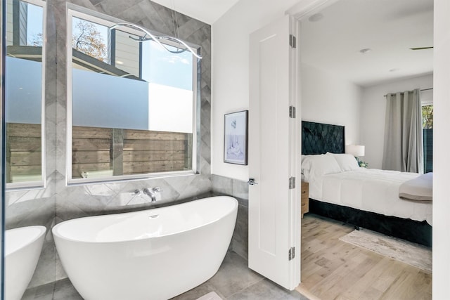 bathroom with tile walls, hardwood / wood-style floors, and a bathing tub