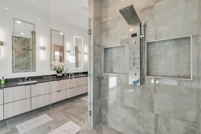 bathroom with a tile shower and vanity