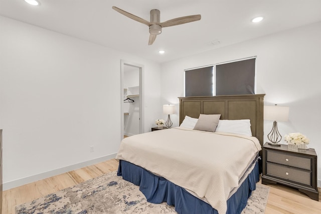 bedroom featuring a walk in closet, ceiling fan, and light hardwood / wood-style flooring