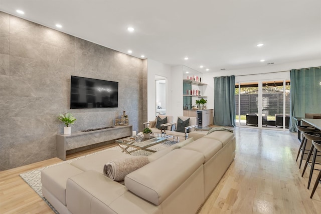 living room featuring tile walls, light wood-type flooring, and beverage cooler