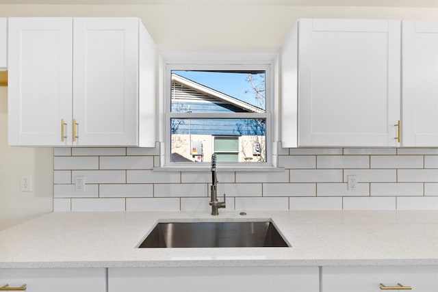3506 Mcdonald Way, Garland, TX 75041 - kitchen featuring a sink, white cabinets, decorative backsplash, and light stone counters