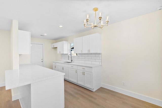 kitchen with kitchen peninsula, decorative light fixtures, decorative backsplash, white cabinets, and sink