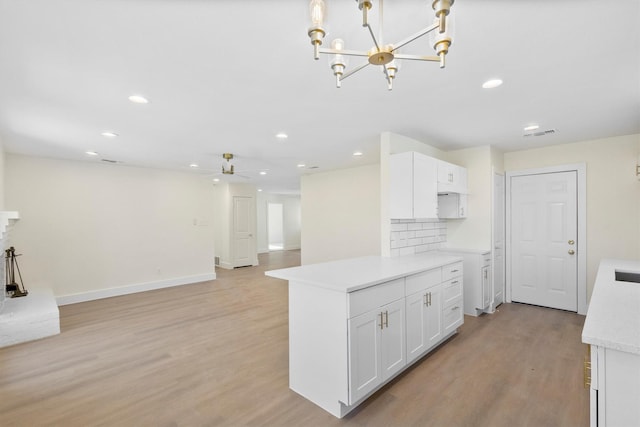 kitchen featuring ceiling fan with notable chandelier, light hardwood / wood-style floors, white cabinets, and tasteful backsplash