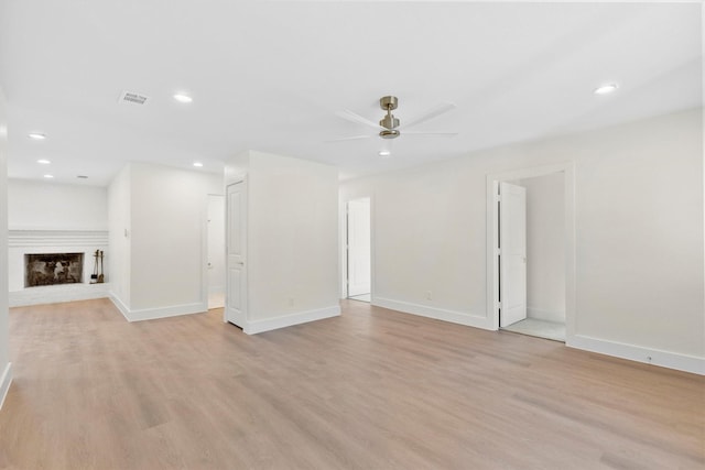 unfurnished living room featuring a brick fireplace, ceiling fan, and light hardwood / wood-style flooring