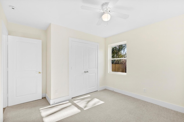 unfurnished bedroom featuring ceiling fan, light colored carpet, and a closet