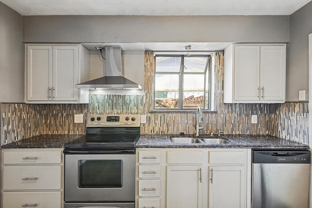 kitchen featuring wall chimney range hood, decorative backsplash, white cabinets, appliances with stainless steel finishes, and sink