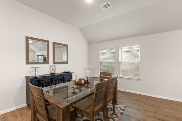 dining room featuring visible vents, baseboards, vaulted ceiling, and wood finished floors