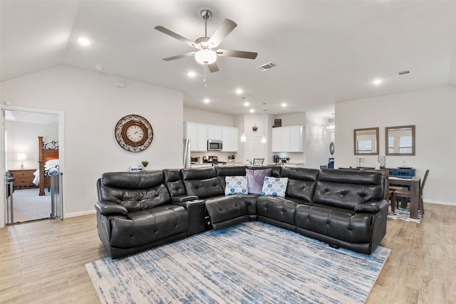 living area featuring light wood finished floors, visible vents, and vaulted ceiling