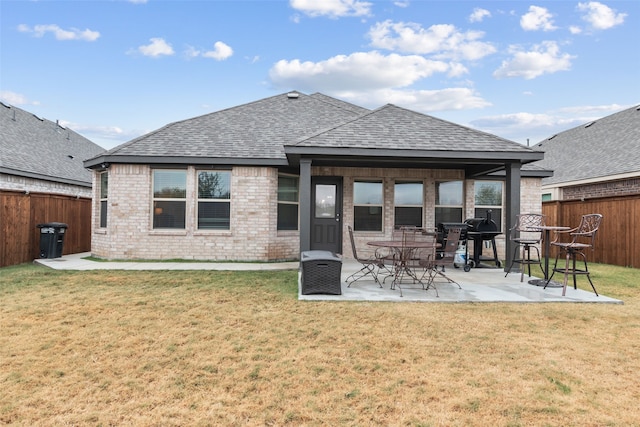 back of house featuring a fenced backyard, a lawn, and brick siding