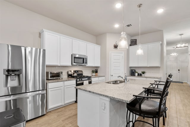 kitchen with visible vents, stainless steel appliances, light wood-style floors, white cabinetry, and a sink