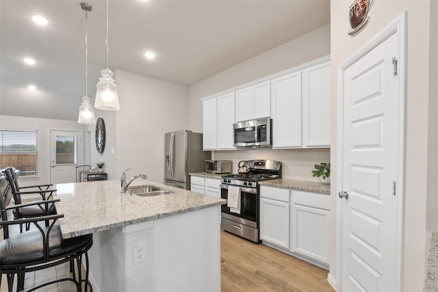 kitchen featuring a center island with sink, light wood-style flooring, a breakfast bar area, stainless steel appliances, and a sink