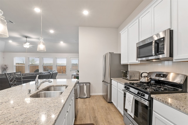 kitchen with stainless steel appliances, a sink, white cabinetry, light wood-style floors, and open floor plan