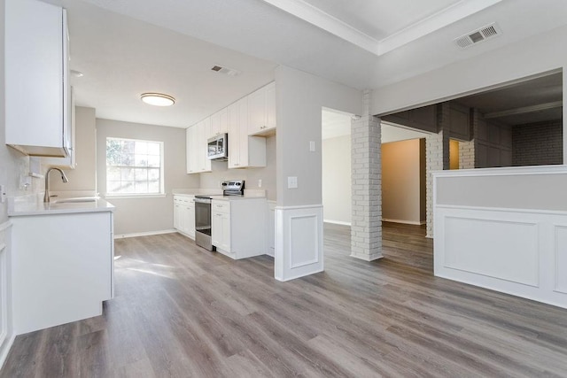 kitchen featuring stainless steel appliances, ornate columns, white cabinetry, and sink