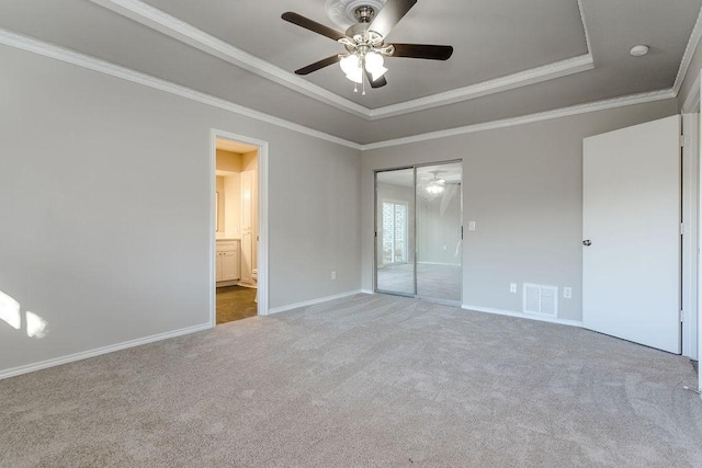 unfurnished bedroom with a raised ceiling, ceiling fan, crown molding, and carpet flooring