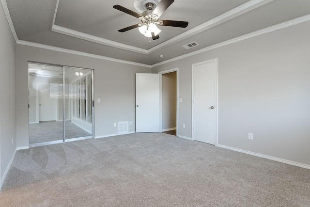 unfurnished bedroom with ceiling fan, crown molding, a tray ceiling, and light carpet