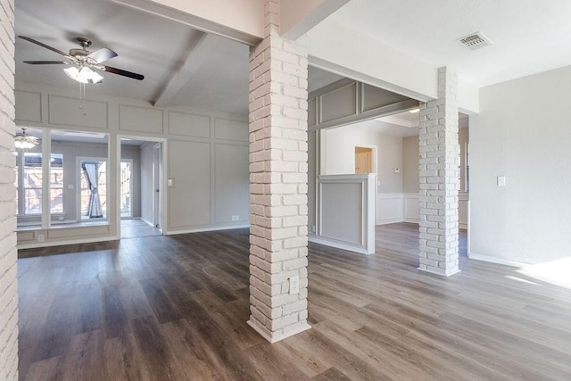 unfurnished living room featuring decorative columns, ceiling fan, and dark wood-type flooring