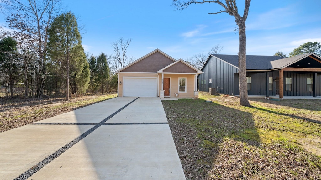 view of front of home with a porch, a front yard, central AC unit, and a garage