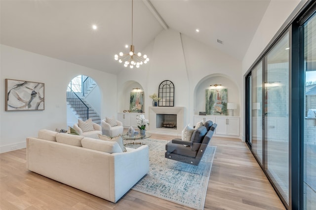 living room with high vaulted ceiling, a chandelier, beamed ceiling, and light hardwood / wood-style flooring