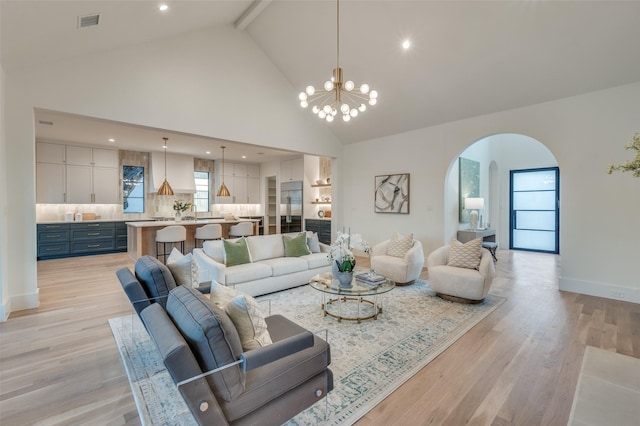 living room with beamed ceiling, light hardwood / wood-style flooring, high vaulted ceiling, and a chandelier