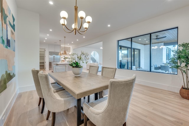 dining space with light hardwood / wood-style floors and ceiling fan with notable chandelier