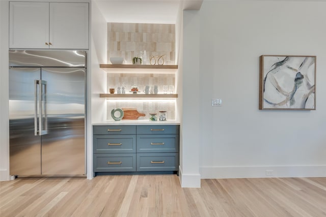 bar with stainless steel built in refrigerator and light hardwood / wood-style floors