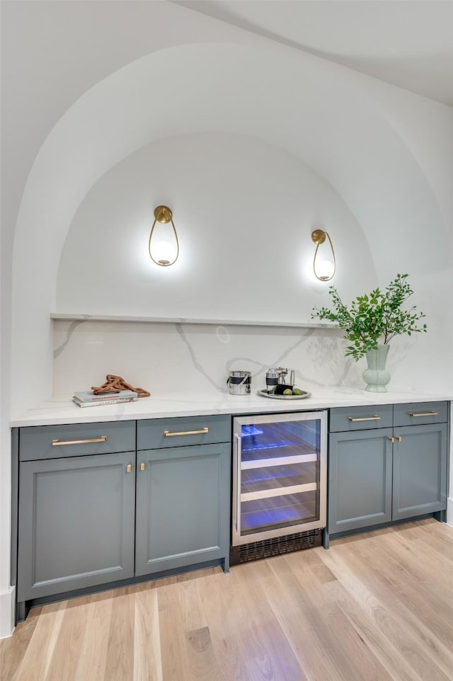 bar featuring wine cooler and light hardwood / wood-style flooring