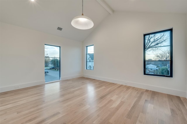 unfurnished room with light hardwood / wood-style floors and lofted ceiling with beams