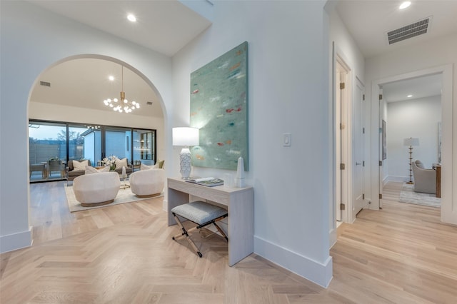 hall with a chandelier and light parquet floors