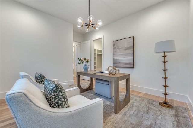 home office with light hardwood / wood-style floors and a notable chandelier