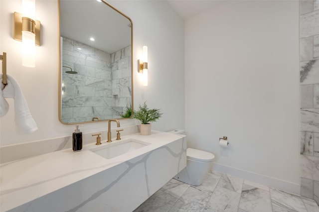 bathroom with toilet, vanity, and tiled shower