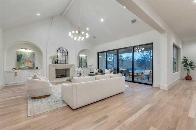 living room with high vaulted ceiling, a notable chandelier, and light hardwood / wood-style flooring