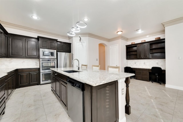 kitchen featuring stainless steel appliances, a breakfast bar, tasteful backsplash, a kitchen island with sink, and sink