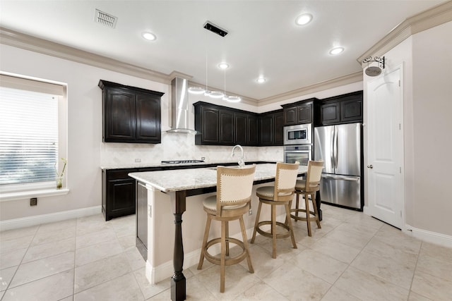 kitchen featuring a kitchen island with sink, stainless steel appliances, light stone countertops, wall chimney exhaust hood, and tasteful backsplash