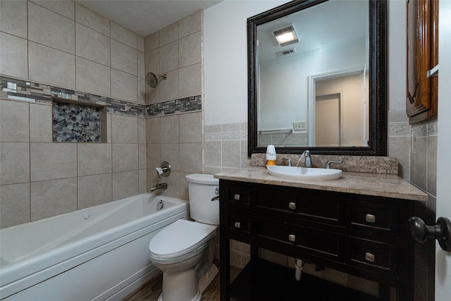 full bathroom with tile walls, toilet, tiled shower / bath, and vanity