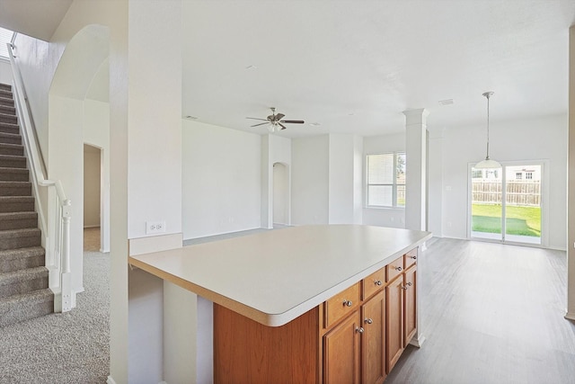 kitchen with a center island, ceiling fan, ornate columns, and hanging light fixtures