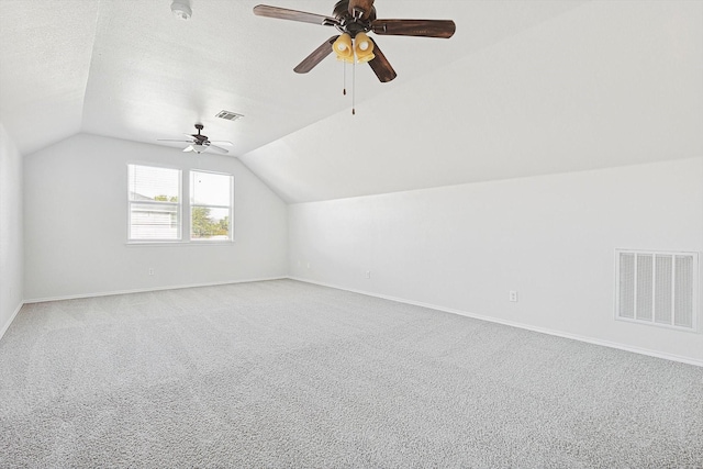 additional living space with ceiling fan, vaulted ceiling, carpet floors, and a textured ceiling