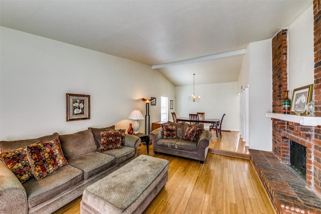 living room featuring lofted ceiling, a fireplace, hardwood / wood-style flooring, and a chandelier