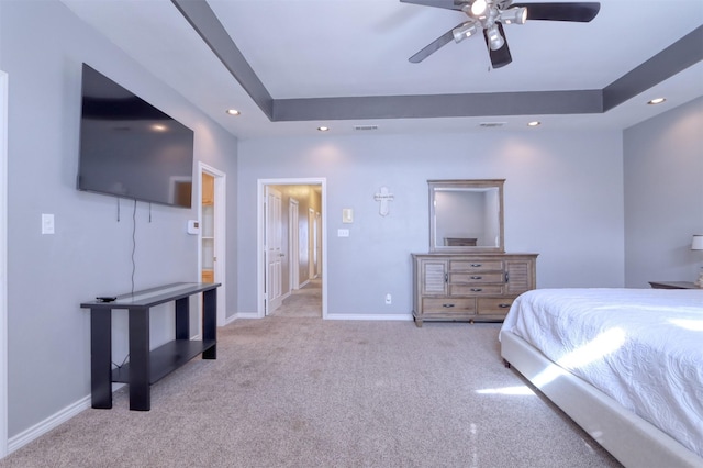 carpeted bedroom featuring ceiling fan and a raised ceiling