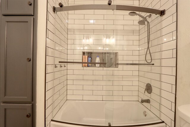 bathroom with toilet and tiled shower / bath